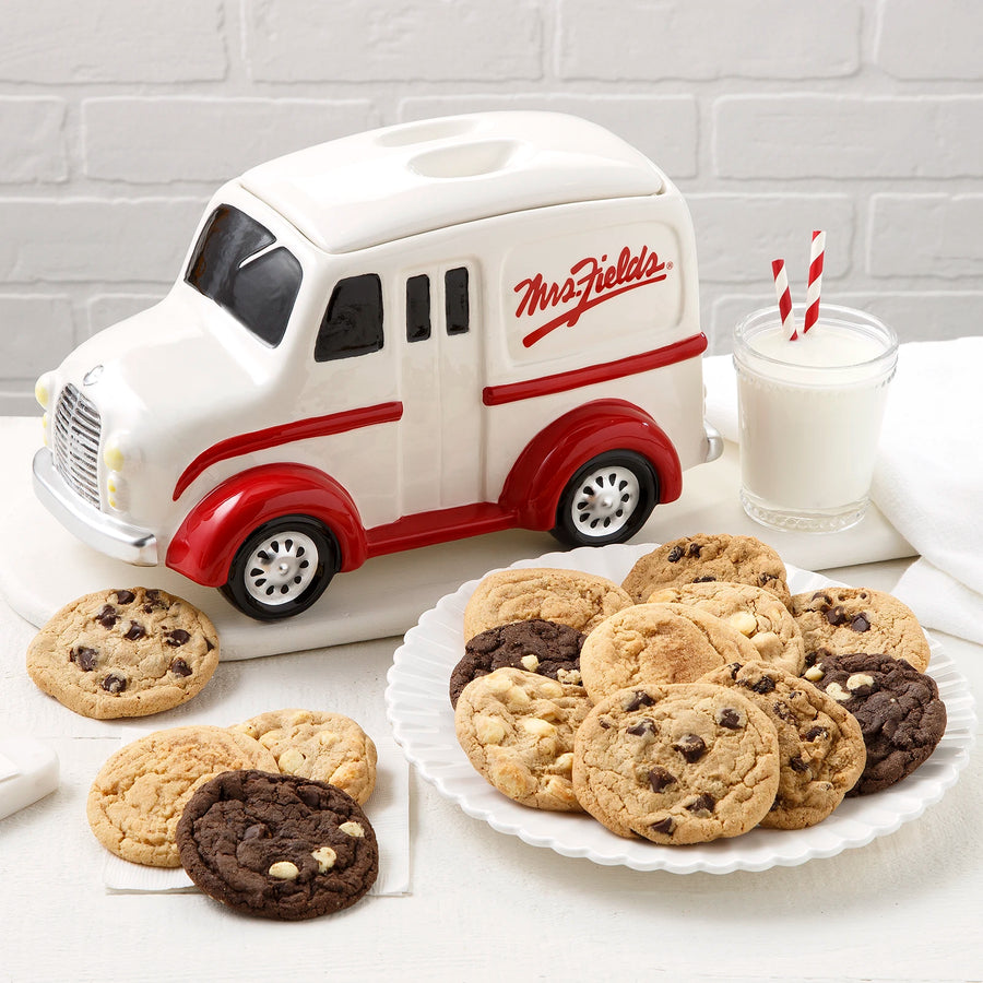 White and red cookie jar shaped like a milik truck with the Mrs. Fields signature logo on it surrounded by an assortment of fourteen Mrs. Fields original cookies.