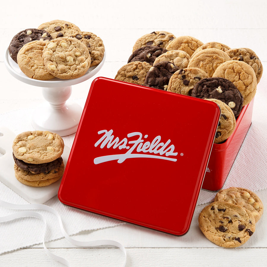 Mrs. Fields signature red cookie tin with an assortment of two original cookies on a white surface.