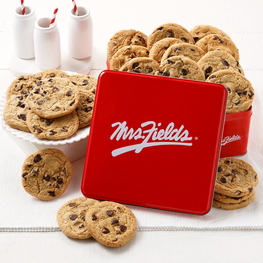 Mrs. Fields signature red cookie tin with two dozen semi-sweet chocolate chip cookies on a white surface with milk bottles.