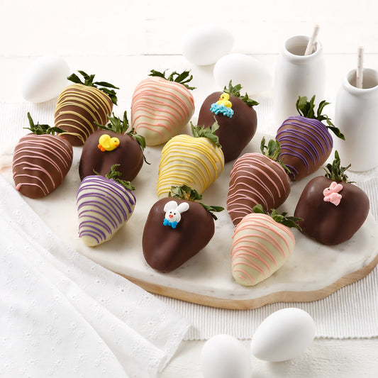 Twelve St. Patrick's Day themed chocolate covered strawberries with green chocolate drizzles and shamrock sprinkles on a white platter with white dishes and glasses of milk.