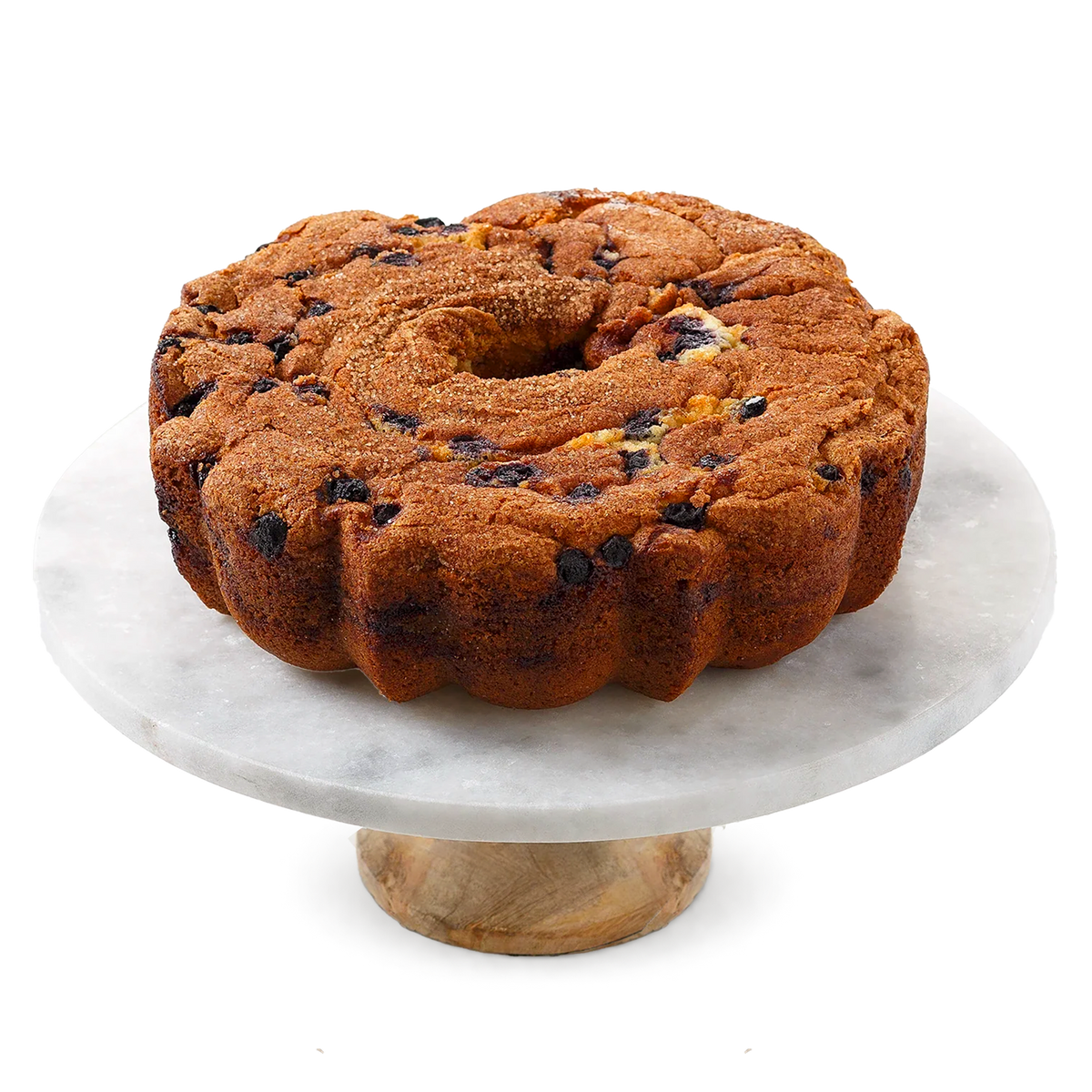 A ring-shaped fruit cake with visible blueberries and dried fruit pieces, displayed on a round white marble cake stand with a wooden base against a white background.