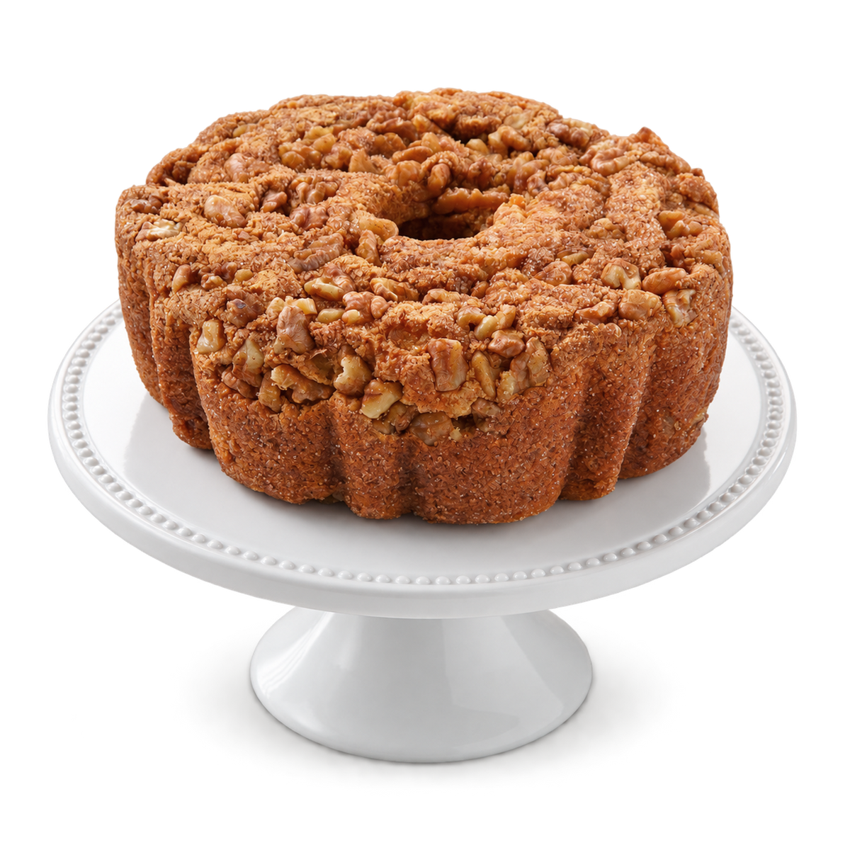 A ring-shaped cinnamon walnut baked cake with a crumb topping and chopped nuts, displayed on a white pedestal cake stand.