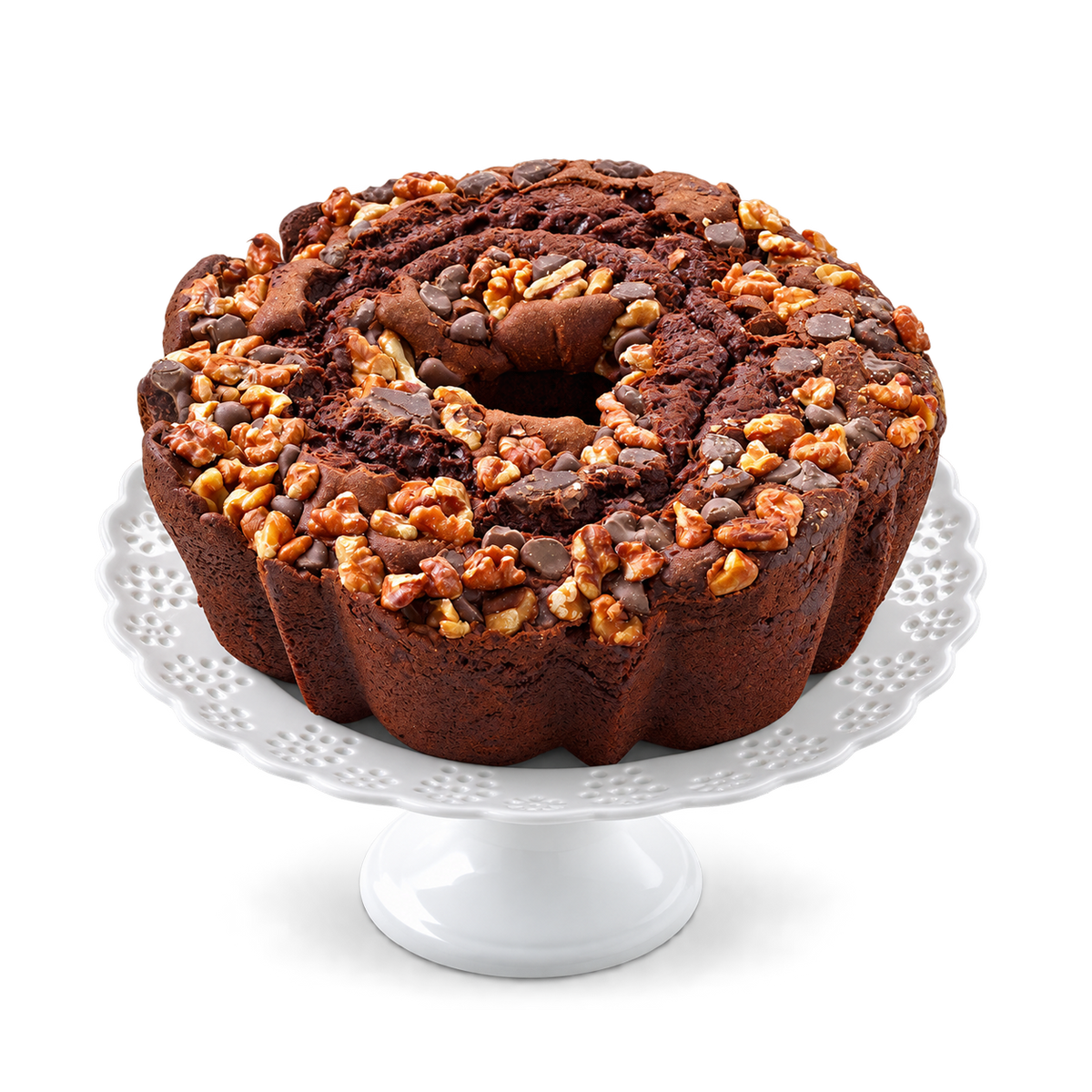 A ring-shaped chocolate cake topped with chopped walnuts, chocolate chips, and caramel, displayed on a white ceramic pedestal stand.