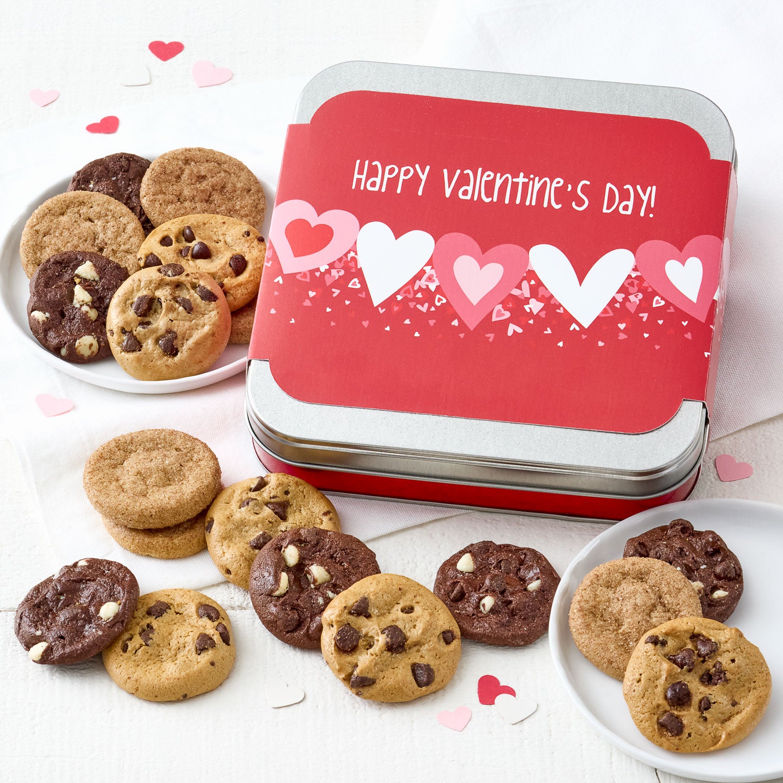 A small gift tin with a Happy Valentine's Day's sleeve and surrounded by an assortment of Nibblers.