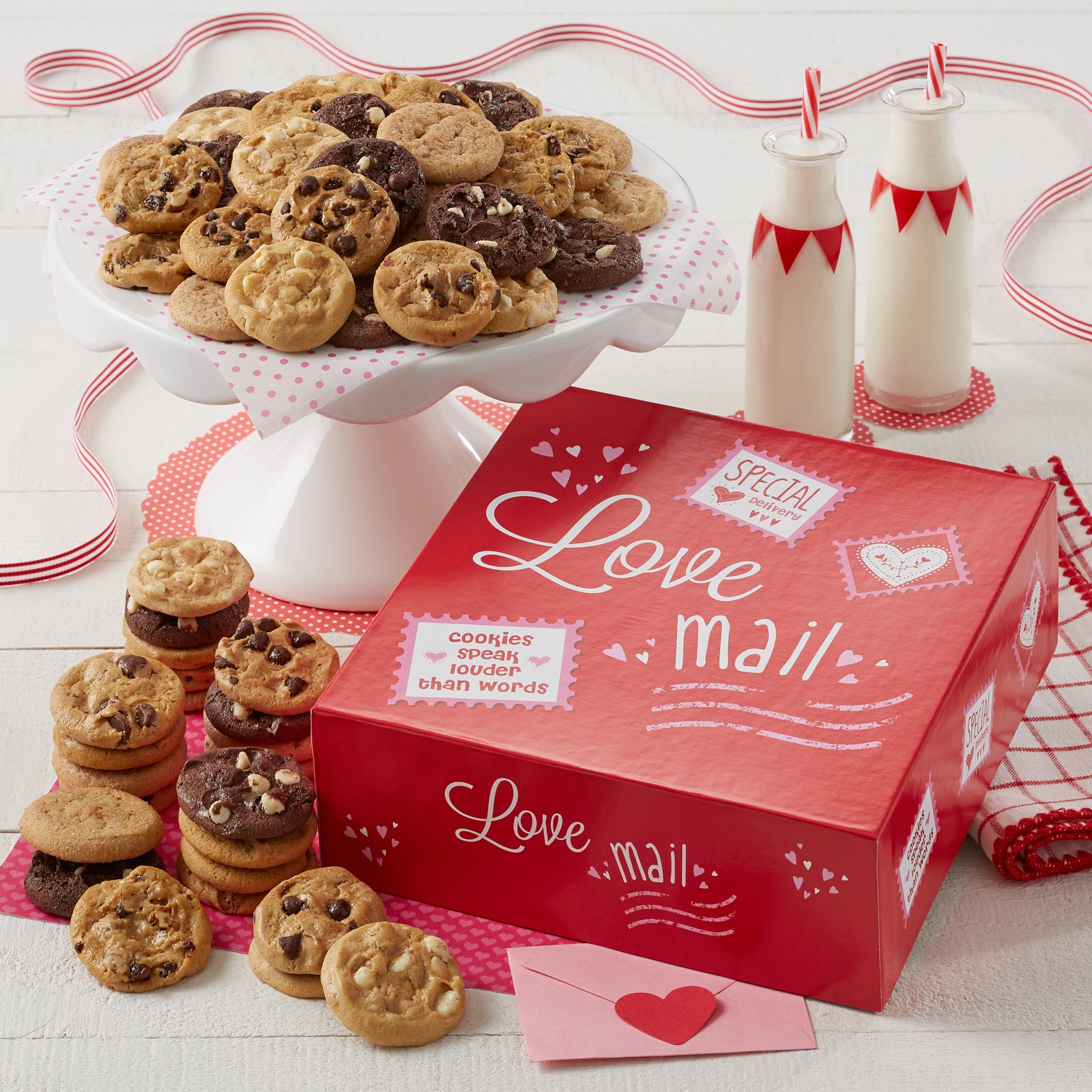 A red gift box decorated with valentines with the sentiment Love mail and surrounded with an assortment of Nibblers.