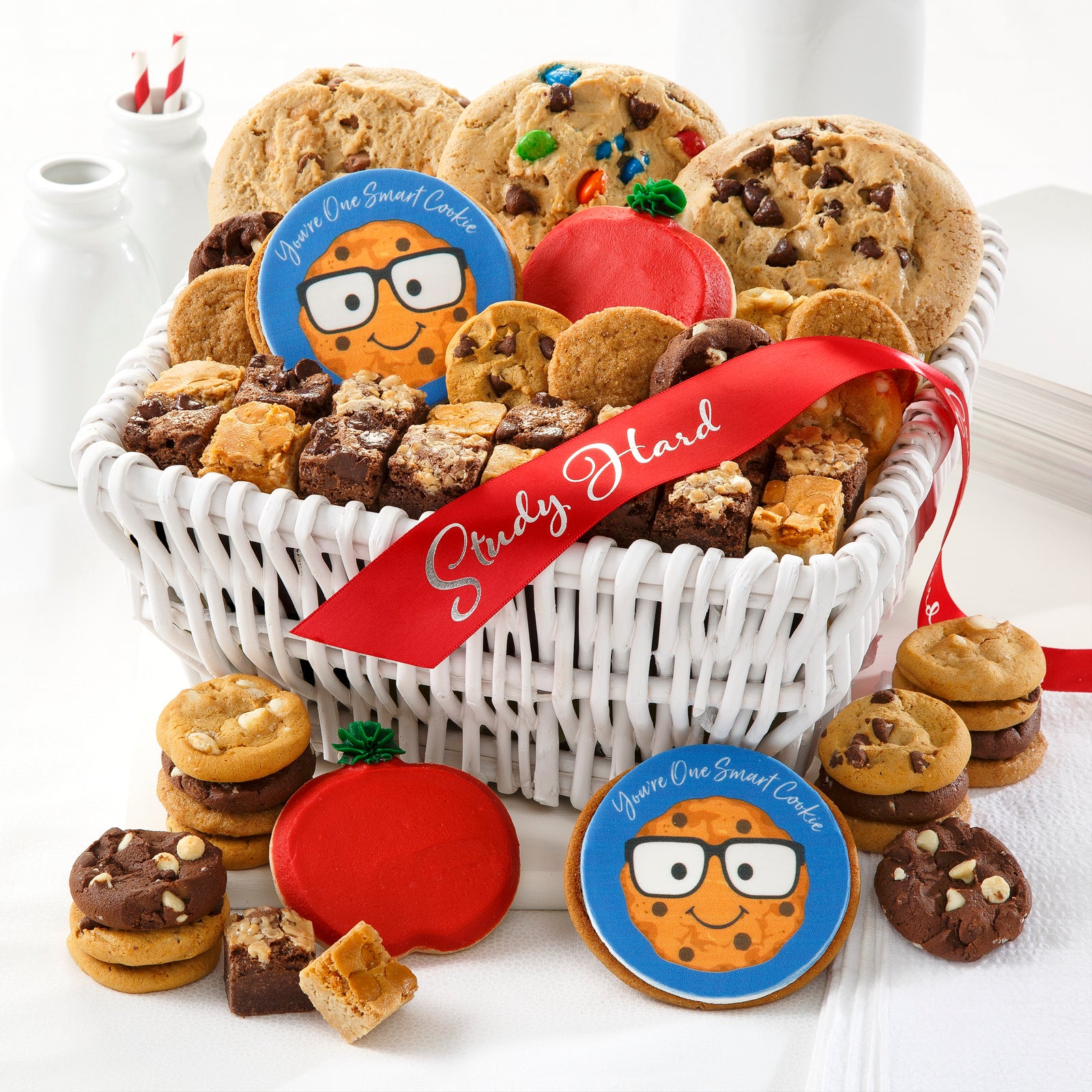 A small white basket filled with three assorted mega cookies, an assortment of Nibblers®, brownie bites, two frosted apple cookies, and two You're One Smart Cookie logo cookies