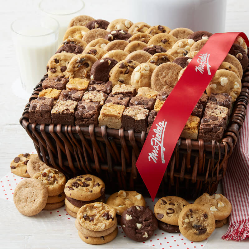 A brown gift basket filled with an assortment of nibblers and brownie bites and tied with a red Mrs. Fields ribbon
